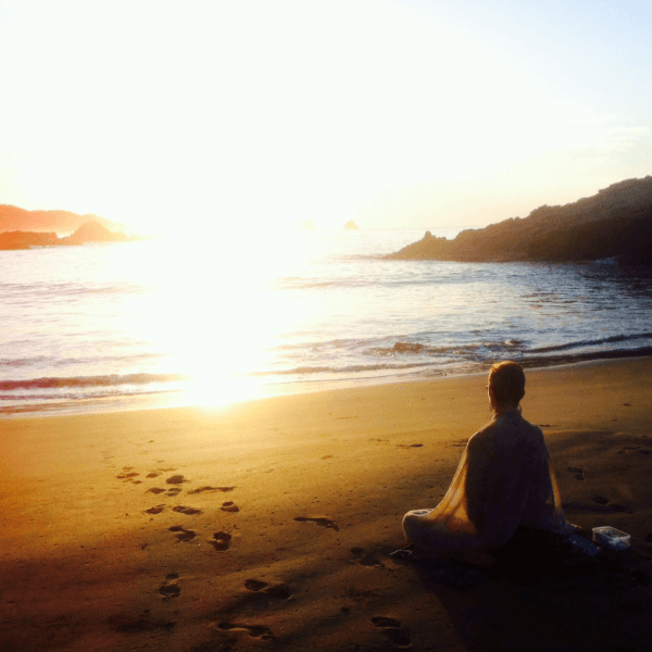 woman sitting on beach at sunset